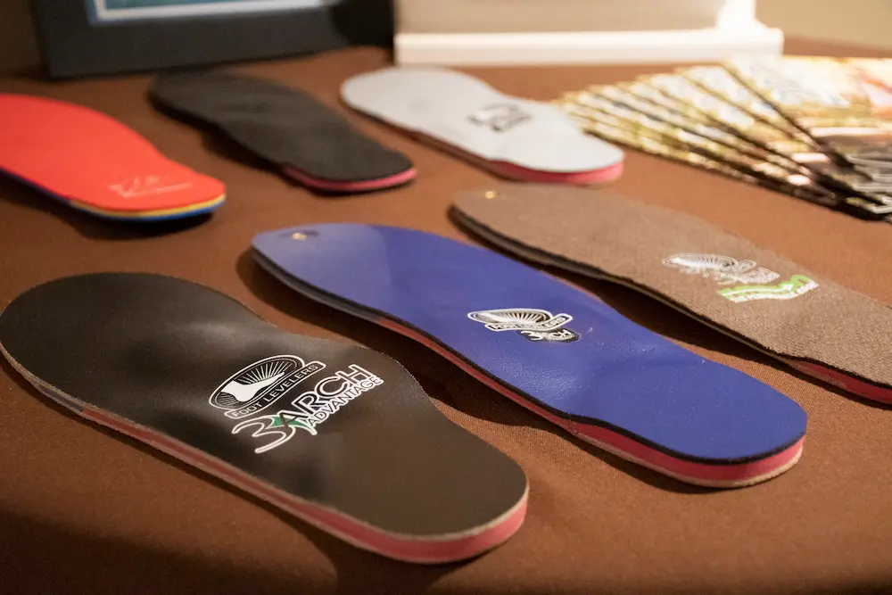 Chiropractor fitting custom orthotic insoles into a patient's shoes